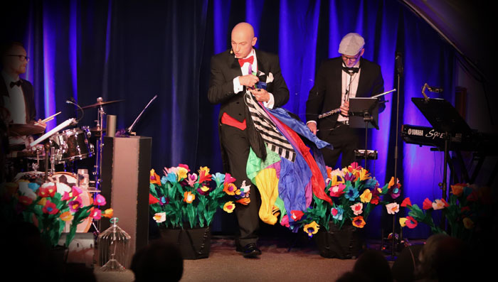 Foto: Nicole Messer Wolf Fisher präsentiert als Cabaret Conférencier auf der Bühne eine magische Zaubershow mit hervorgezauberten Tüchern in der Hand.